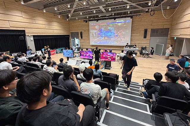 大画面に映し出された対戦を見守る参加者と観客
