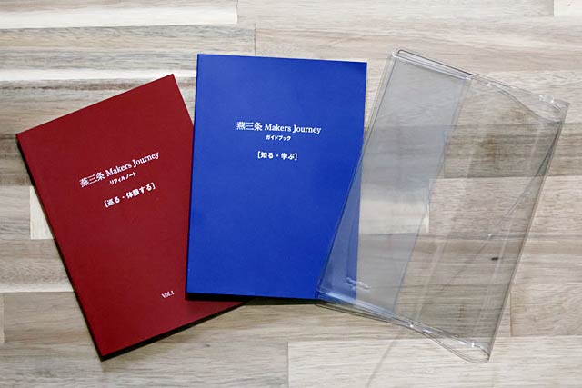 「ガイドブック【知る・学ぶ】」と赤い表紙の「リフィルノート【巡る・体験する】」の2冊セットにビニール製しおり付きブックカバー「BOOKSKIN」が付く