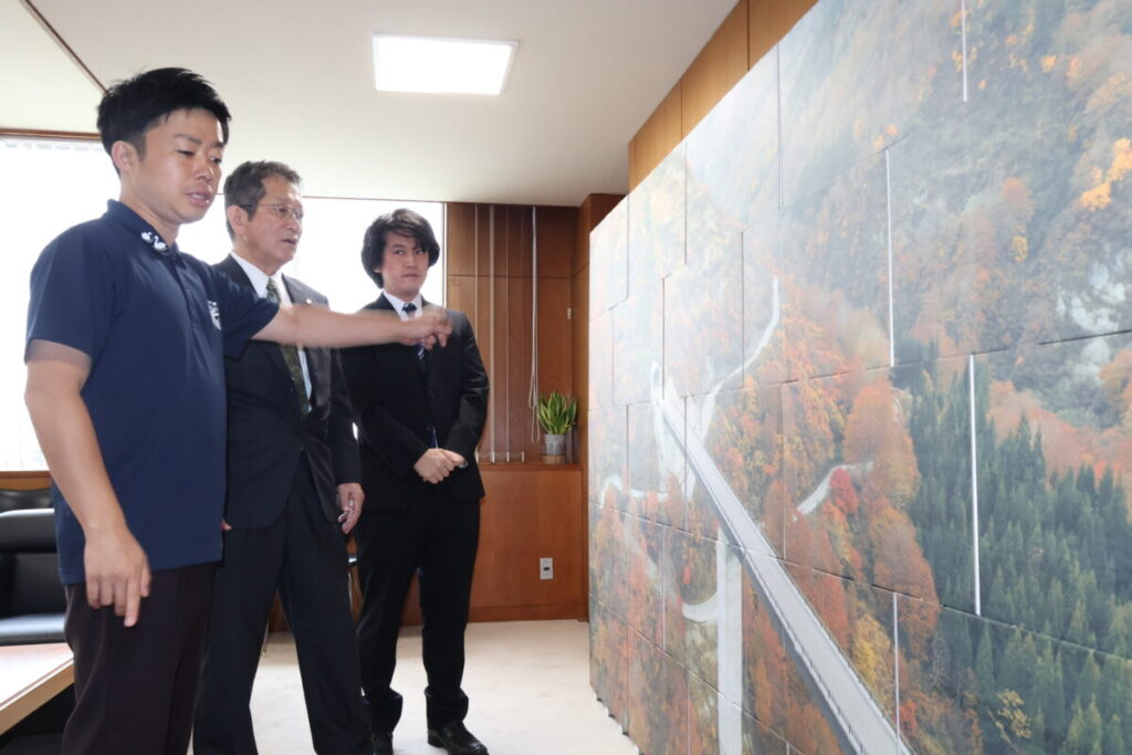 段ボール箱に直接印刷した八十里越天空大橋の写真の迫力に滝沢市長も関心